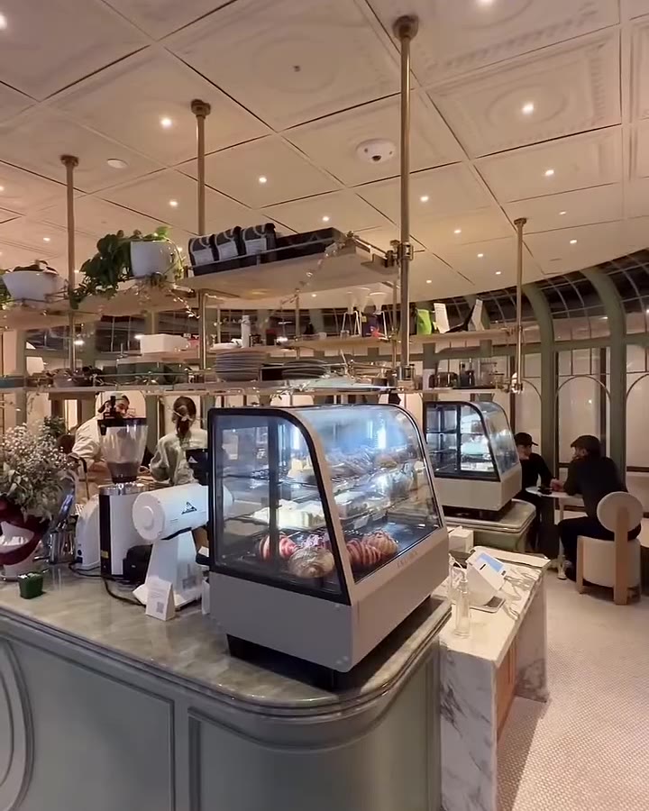 Sage green pastry counter beneath a coffered ceiling at Café X Bica
