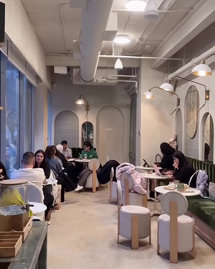 Bright interior at Café X Bica in Toronto with arched mirrors and green banquettes